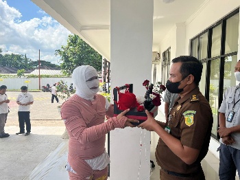 Direktur LOGIS-NTB Fihiruddin menyerahkan paket pakaian dalam wanita kepada Kasi Intel Anak Agung Kusuma Putra